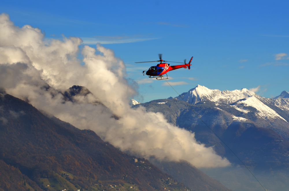 helicopter flying among clouds snow capped mountains